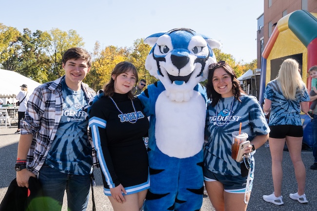 Three students and Blue the mascot celebrate at orientation