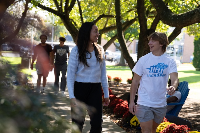 Students touring campus walk through a grove of trees