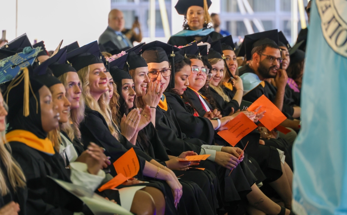 Students sitting in caps and gowns in the front row of the commencement ceremony