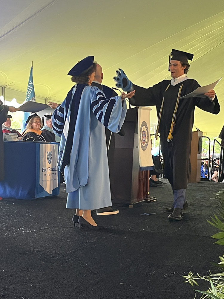 Dr. Prisco embraces graduating student receiving diploma