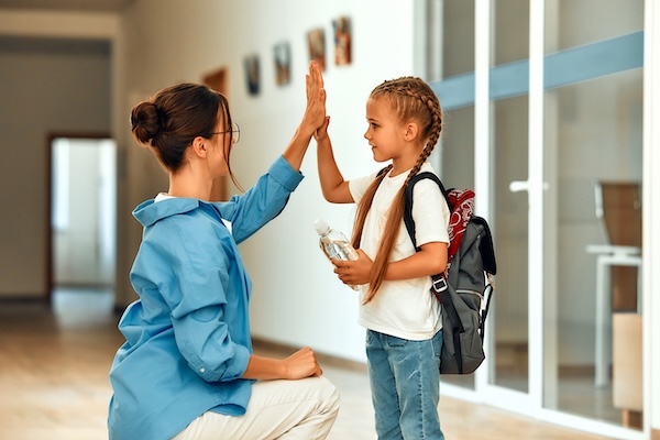 a young student and her teacher high fiving outside a classroom