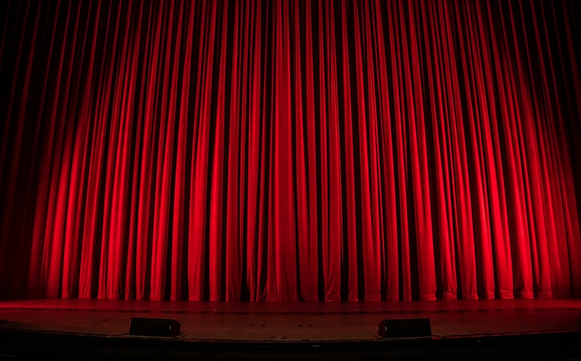 A theater stage with a closed red curtain