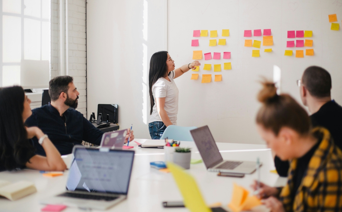 Woman leading meeting in conference room with post-it notes on a whiteboard