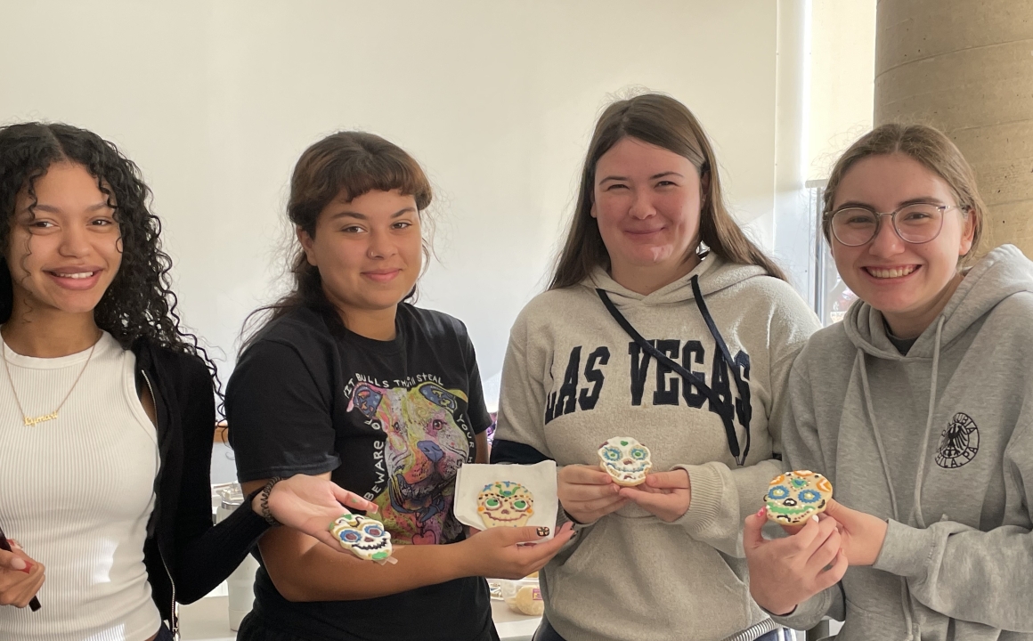 Four students decorate cookies for Day of the Dead.