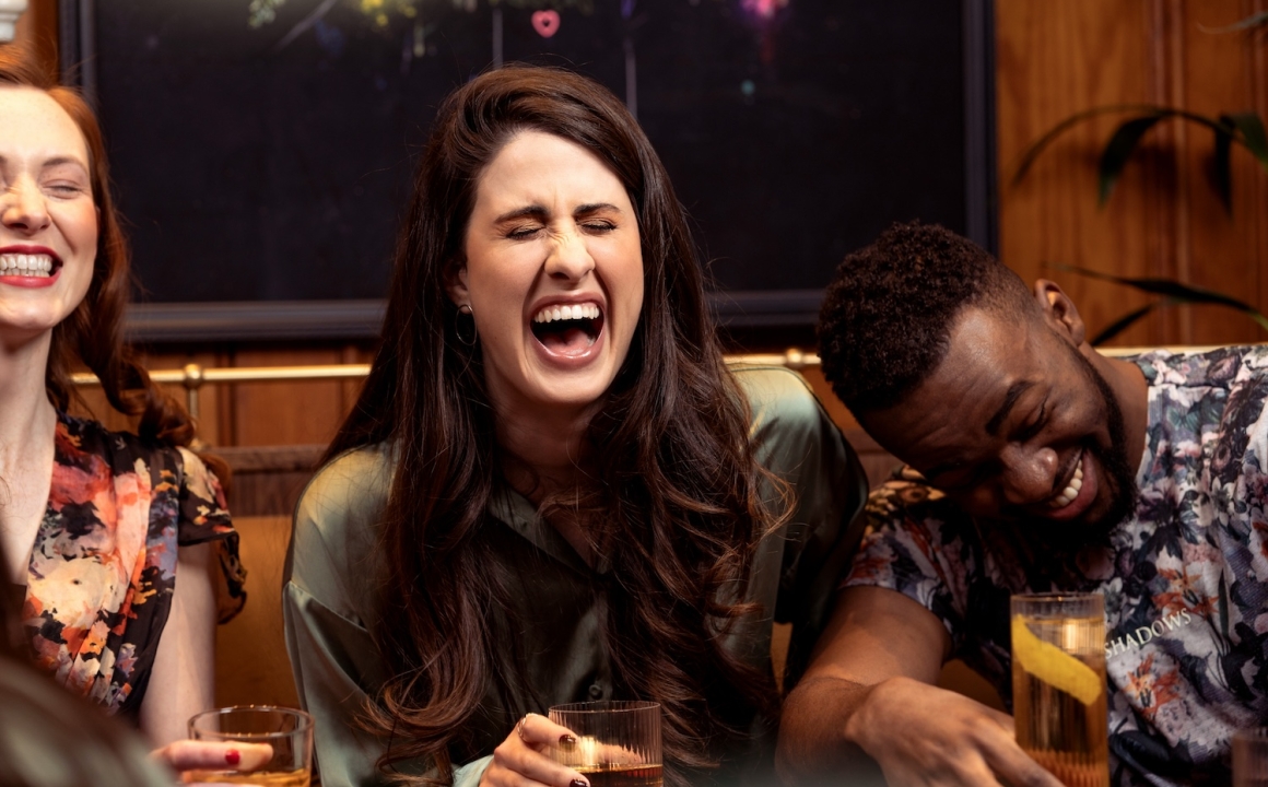 Three people sitting at a restaurant table laughing