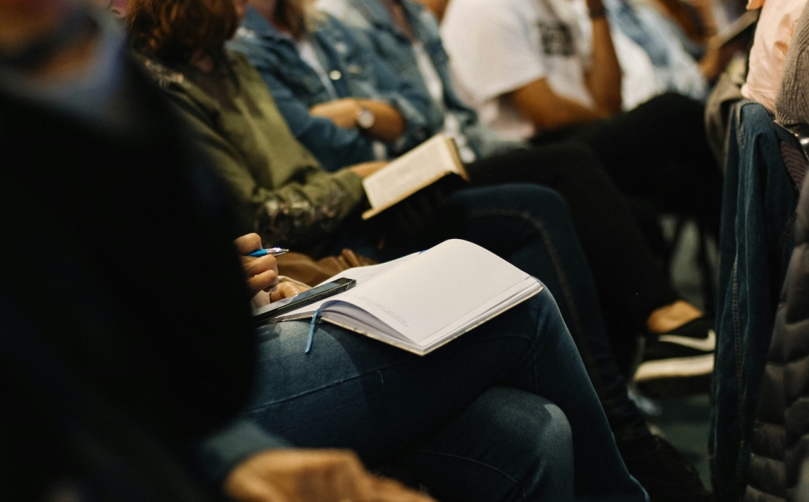 College students sitting in a large lecture class taking notes