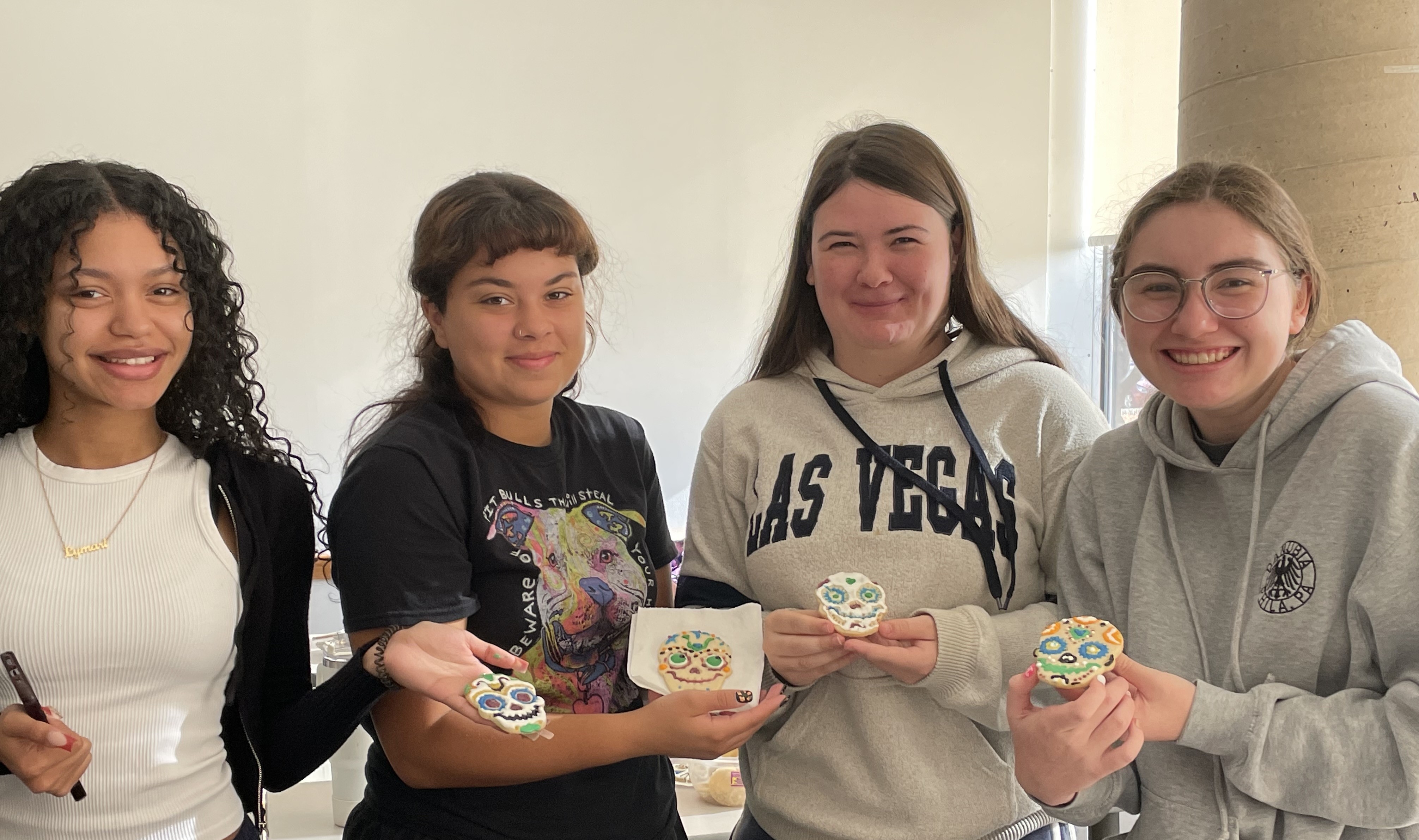 Four students decorate cookies for Day of the Dead.