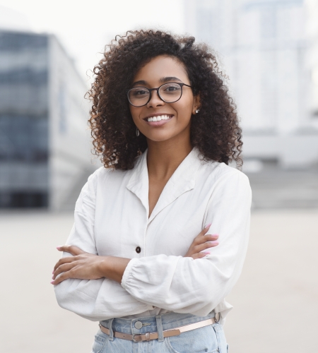 Smiling female business student standing in plaza with arms crossed