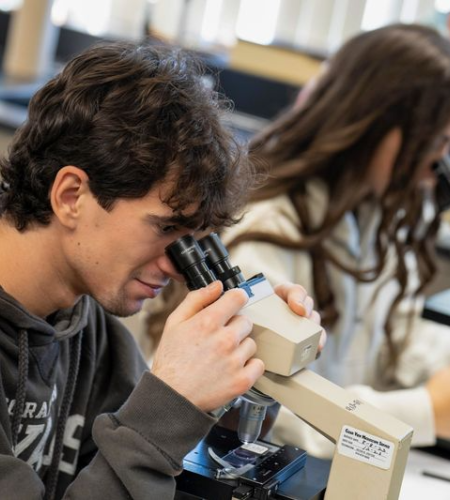 Holy Family University students in a lab looking through microscopes