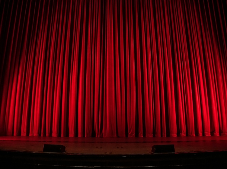 A theater stage with a closed red curtain