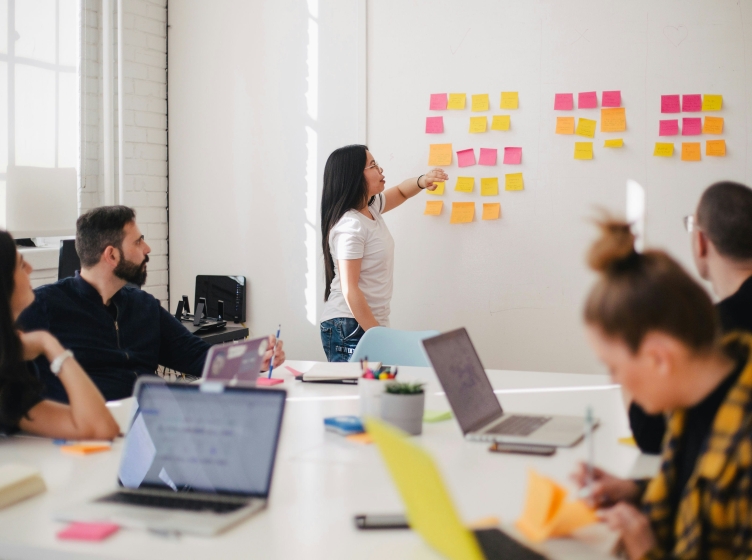 Woman leading meeting in conference room with post-it notes on a whiteboard