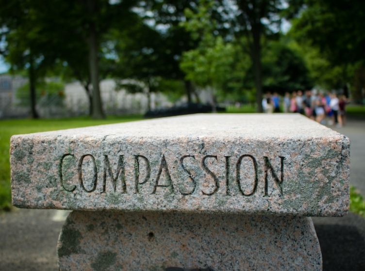 A marble outdoor bench with "Compassion" engraved in it