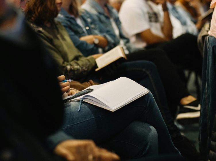 College students sitting in a large lecture class taking notes