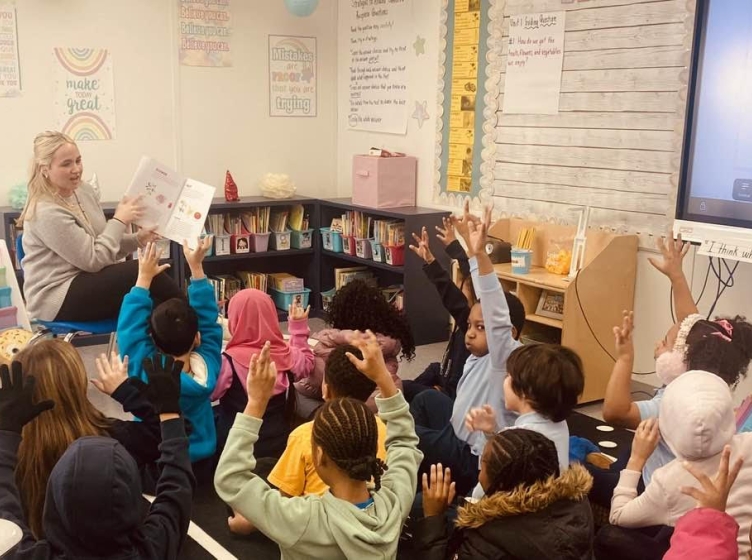 A teacher reading a book to a grade school classroom of children