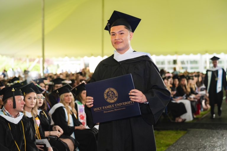 Student holding up his diploma after receiving it at Commencement